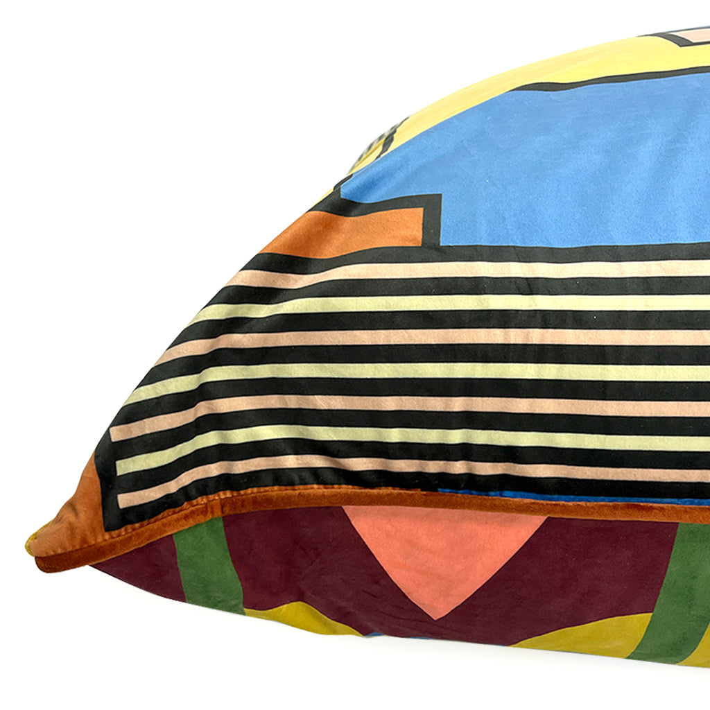 Colorful velvet geometric-patterned floor pillow with stripes and shapes on a white background for home decor and meditation.