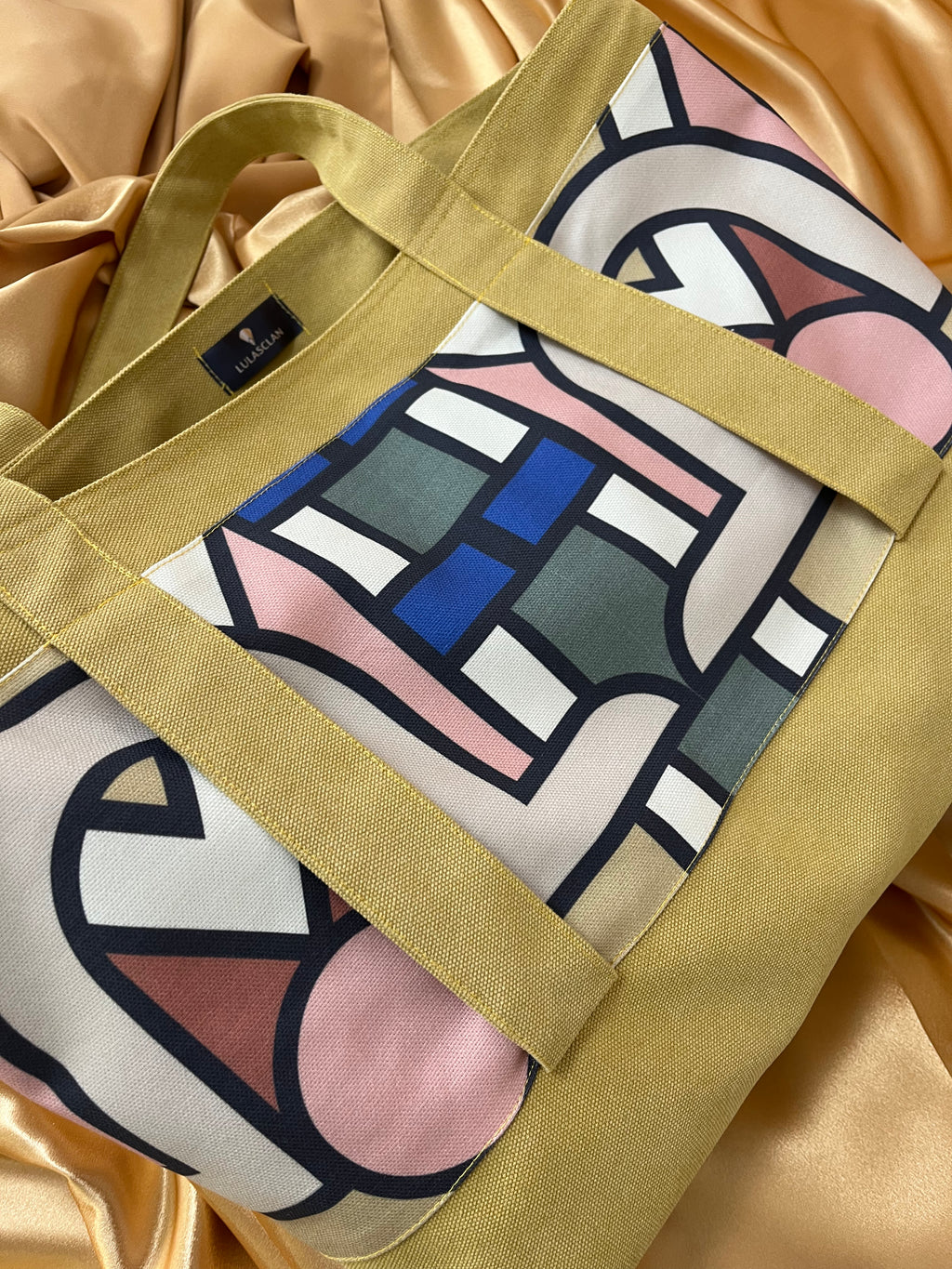 Tote bag with abstract geometric pattern on a gold fabric background