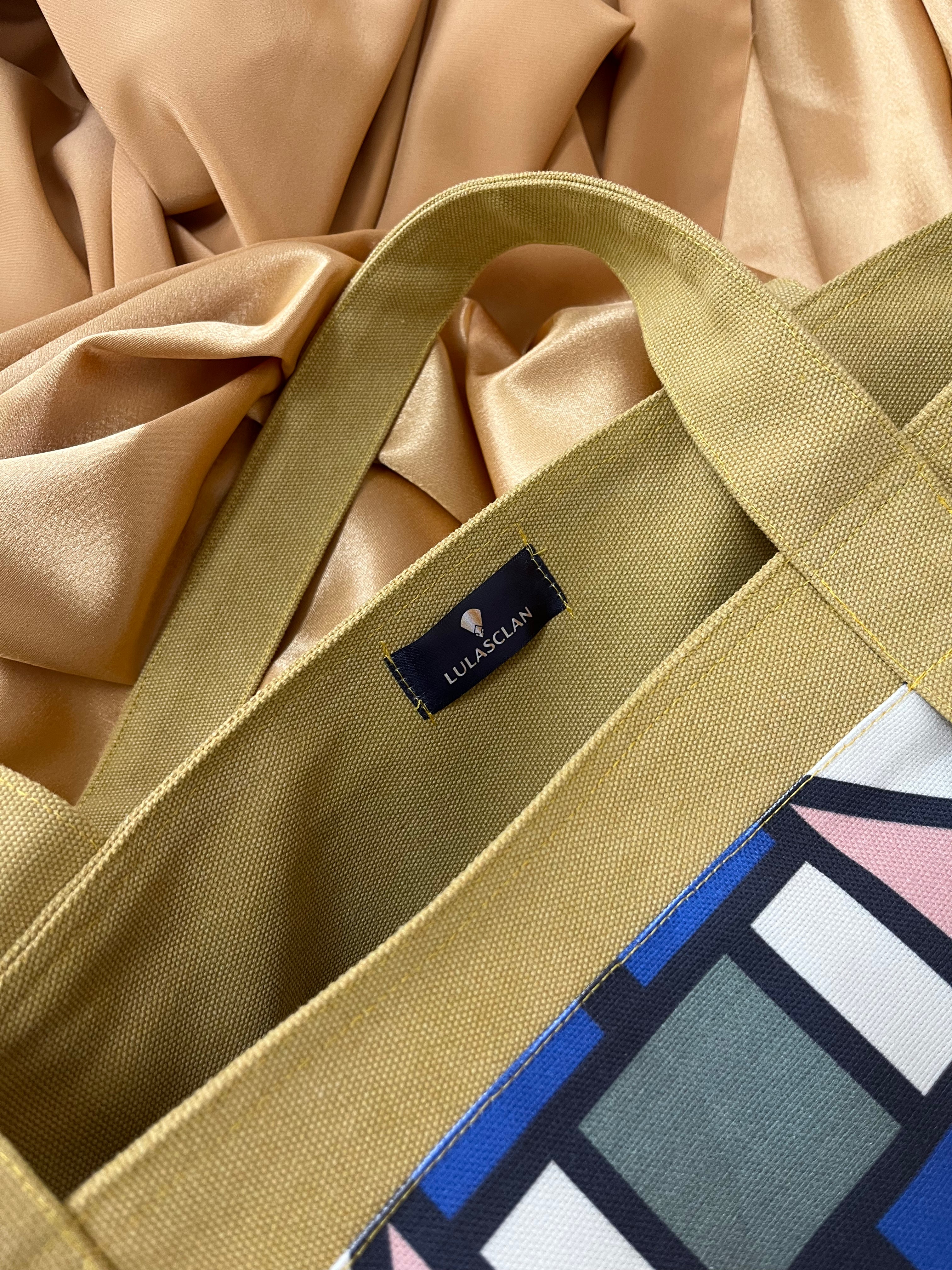 Marigold tote bag with a visible brand label on a satin fabric background